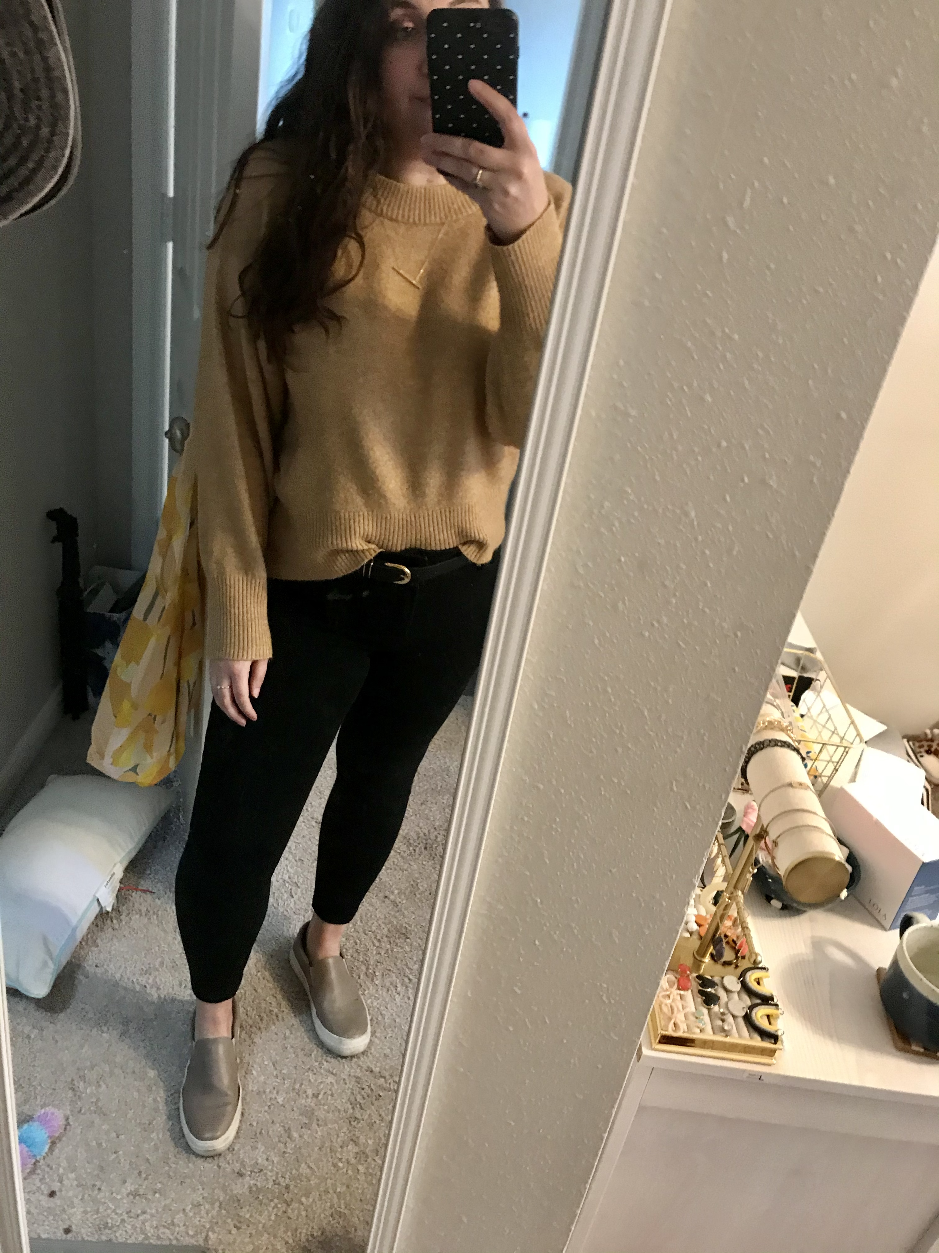 Girl in brown sweater and black jeans with grey slide on sneakers