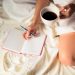 girl drinking coffee in bed writing notes